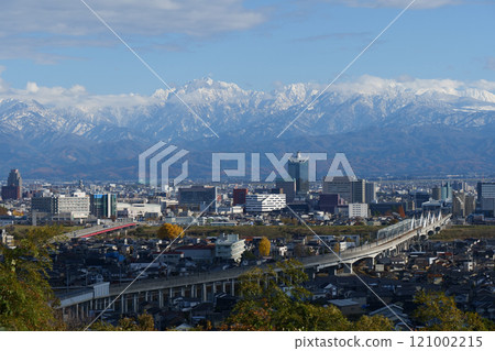 December 2024: Panorama of the Hokuriku Shinkansen, the buildings in the center of Toyama City, and the snow-capped Mount Tsurugi and Mount Tateyama mountain ranges in the Northern Alps 121002215