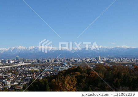 December 2024: Panorama of Toyama city and snow-capped Mount Tsurugi and Mount Yakushi in the Tateyama mountain range in the Northern Alps, with the Hokuriku Shinkansen running through the city 121002229