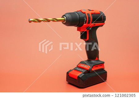 electric cordless screwdriver with a metal drill on a red. isolate 121002305