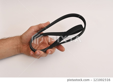 the belt of the car generator. spare parts on a white background in the mechanic's hand 121002316