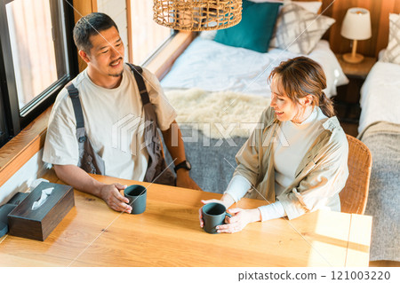 一對夫婦在小屋、小木屋或木屋裡邊喝咖啡邊微笑和交談 121003220
