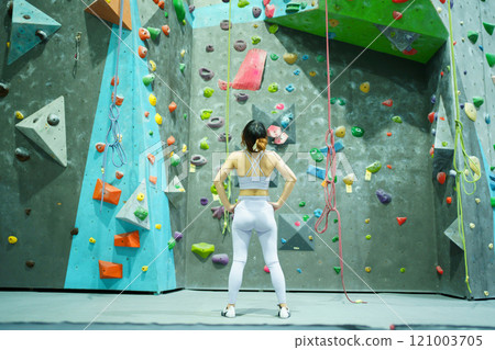 Asian sportswoman practices an indoor rock climbing wall. Healthy and sportive Asian woman is practicing a body strength sport training, woman climb an indoor rock climbing. Asian sportswoman practices an indoor rock climbing wall. Healthy and sportive Asian woman is practicing a body strength sport training, woman climb an indoor rock climbing. 121003705