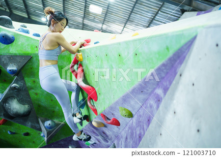 Asian sportswoman practices an indoor rock climbing wall. Healthy and sportive Asian woman is practicing a body strength sport training, woman climb an indoor rock climbing. Asian sportswoman practices an indoor rock climbing wall. Healthy and sportive Asian woman is practicing a body strength sport training, woman climb an indoor rock climbing. 121003710