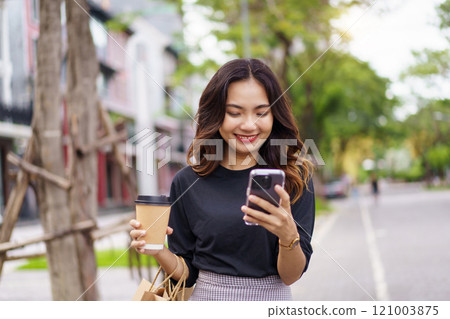 Asian businesswoman walking on the street in city. Smart and good looking Asian businesswoman is walking in the city while using a smartphone for text message and talking to colleague and other. Asian businesswoman walking on the street in city. Smart and good looking Asian businesswoman is walking in the city while using a smartphone for text message and talking to colleague and other. 121003875