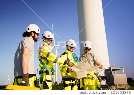 Team of electrical engineer is perform the inspection and maintenance of electric generating windmill turbine. Team of professional electrical engineers in fully safety suit are working and discussing Team of electrical engineer is perform the inspection and maintenance of electric generating windmill turbine. Team of professional electrical engineers in fully safety suit are working and discussing 121003876