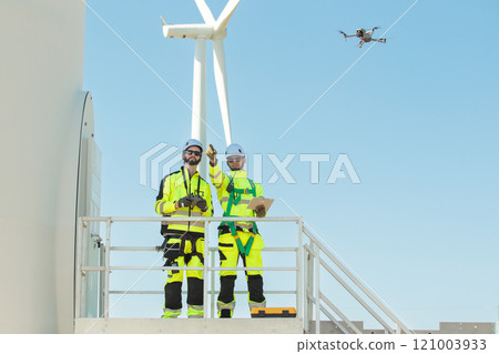 Team of electrical engineer is perform the inspection and maintenance of electric generating windmill turbine. Team of professional electrical engineers in fully safety suit are working and discussing Team of electrical engineer is perform the inspection and maintenance of electric generating windmill turbine. Team of professional electrical engineers in fully safety suit are working and discussing 121003933