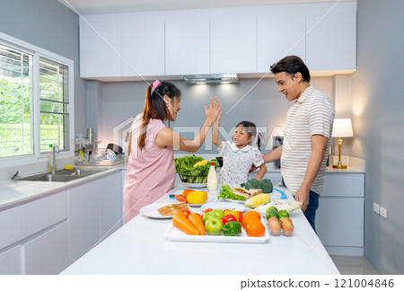 Little Asian girl clap hands together with pregnant mother and stay in kitchen to prepare for cooking with happiness. Little Asian girl clap hands together with pregnant mother and stay in kitchen to prepare for cooking with happiness. 121004846