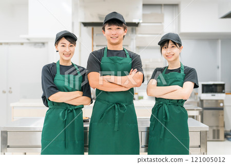 Male and female kitchen staff and cooking staff (arms crossed) in the kitchen and back room Male and female kitchen staff and cooking staff (arms crossed) in the kitchen and back room 121005012