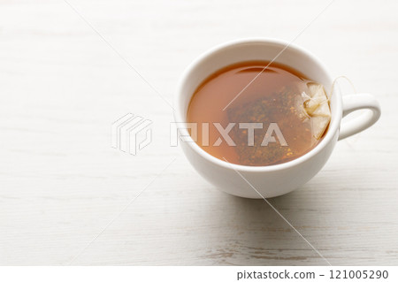 Cup of hot tea blended from rooibos, spearmint, apple, baobab on white wooden table. 121005290