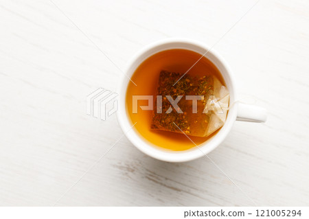 Cup of hot tea blended from rooibos, spearmint, apple, baobab on white wooden table. Cup of hot tea blended from rooibos, spearmint, apple, baobab on white wooden table. 121005294