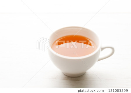 Cup of hot tea blended from rooibos, spearmint, apple, baobab on white wooden table. 121005299