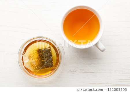 Cup of hot tea blended from rooibos, spearmint, apple, baobab on white wooden table. 121005303