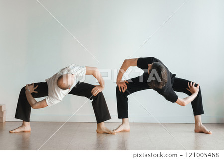 two young athletes practice yoga in the gym. Joint training, indoors, studio. The concept of a healthy lifestyle two young athletes practice yoga in the gym. Joint training, indoors, studio. The concept of a healthy lifestyle 121005468