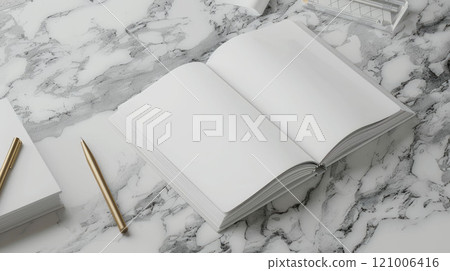 An open book with white pages on a marble surface, with stationery elements nearby 121006416