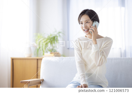 Lifestyle: A woman sitting on a sofa talking on her smartphone 121006573