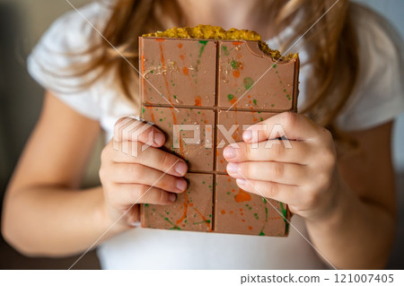 Dubai chocolate with pistachio paste and kataifi dough in hands of little girl. Confectionery handmade sweets at home in the kitchen. Dubai chocolate with pistachio paste and kataifi dough in hands of little girl. Confectionery handmade sweets at home in the kitchen. 121007405