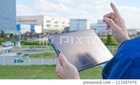 A male worker using a tablet PC in front of a building 121007478