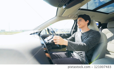 Photo of a smiling male driver driving a car Photo of a smiling male driver driving a car 121007483