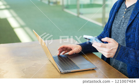 Men using laptops and smartphones Men using laptops and smartphones 121007484