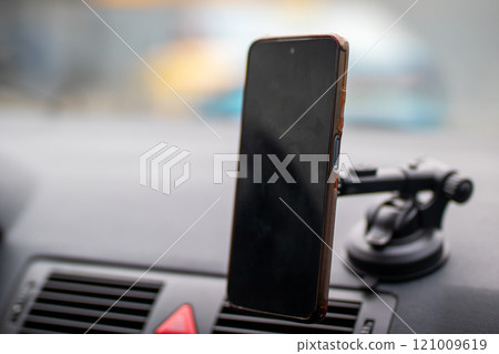 A cell phone is on a suction cup on a cars dashboard 121009619