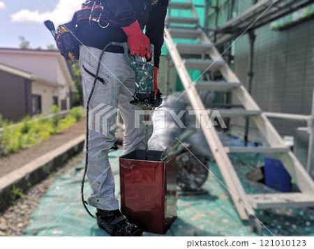 A male craftsman mixing paint for exterior wall painting with a mixer A male craftsman mixing paint for exterior wall painting with a mixer 121010123
