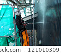 A male craftsman uses high-pressure washing to prepare the exterior walls of a wooden house for painting 121010309