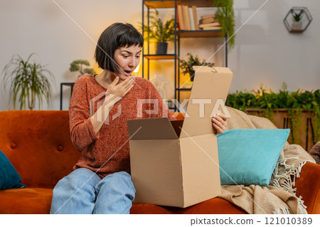 Happy woman shopper unpacking cardboard box delivery parcel online shopping purchase at home room 121010389