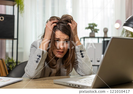 Tired sleepy young businesswoman sitting at home office desk with laptop overworked lazy bored 121010417