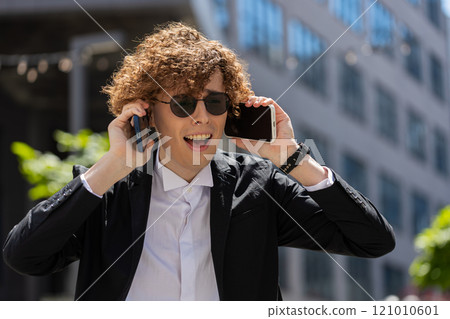 Angry confused puzzled business man shouting talking on two mobile phones on street outside office Angry confused puzzled business man shouting talking on two mobile phones on street outside office 121010601