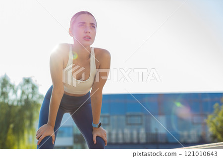 Tired young athlete woman jogger in sportswear resting after hard training in urban city park Tired young athlete woman jogger in sportswear resting after hard training in urban city park 121010643