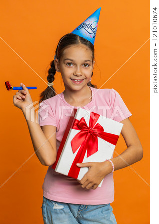 Happy excited lucky girl wearing birthday hat cone blow pipe celebrating party success win victory Happy excited lucky girl wearing birthday hat cone blow pipe celebrating party success win victory 121010674