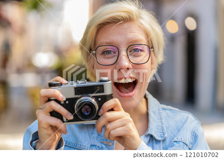 Portrait of happy young woman tourist traveler taking photos using retro camera on city urban street Portrait of happy young woman tourist traveler taking photos using retro camera on city urban street 121010702