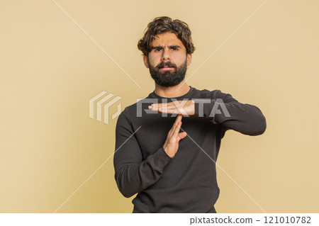 Upset young Lebanese man showing timeout gesture, limit or stop sign against beige background Upset young Lebanese man showing timeout gesture, limit or stop sign against beige background 121010782