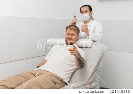 Trichologist doing man improve hair growth procedure, dermapen microneedling, vitamin injections Trichologist doing man improve hair growth procedure, dermapen microneedling, vitamin injections 121010816
