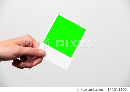 photo frame in girl's hands. instant printed photo in female hand close-up, layout for your advertising. snapshot of happy moment in life green screen 121011102