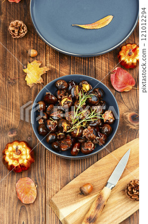 Cracked roasted chestnuts on rustic wooden table. 121012294