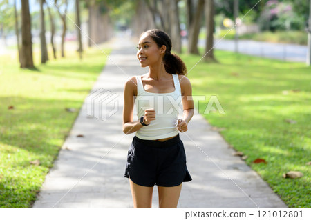 Shot of smiling young woman jogging on a sunny pathway. Healthy and active lifestyle concept Shot of smiling young woman jogging on a sunny pathway. Healthy and active lifestyle concept 121012801