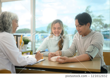 Happy couple discussing health checkup results with a doctor during consultation at a modern clinic. Happy couple discussing health checkup results with a doctor during consultation at a modern clinic. 121012832