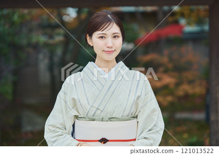 A beautiful woman in a kimono standing in front of an old house 121013522