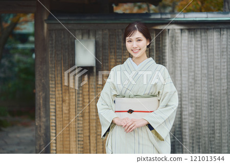 A beautiful woman in a kimono standing in front of an old house A beautiful woman in a kimono standing in front of an old house 121013544