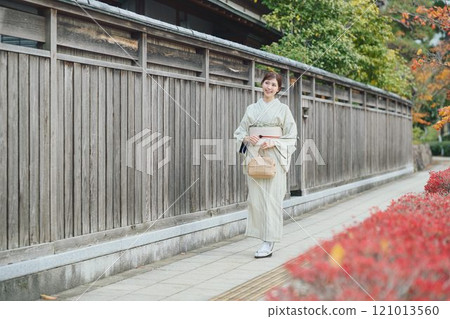 一個穿著和服的女人在一座古老的民宅旁行走 121013560