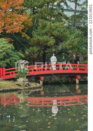 A woman in traditional Japanese clothing standing on a bridge 121013601