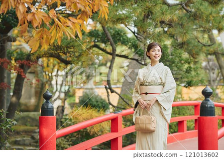 A woman in traditional Japanese clothing standing on a bridge A woman in traditional Japanese clothing standing on a bridge 121013602