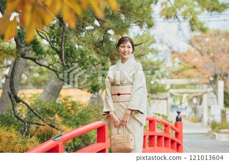 A woman in traditional Japanese clothing standing on a bridge A woman in traditional Japanese clothing standing on a bridge 121013604