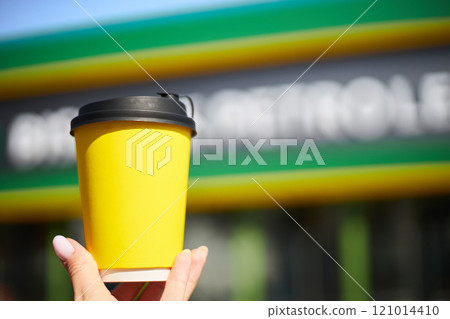 Yellow cardboard cup with a black lid for hot drinks in a woman's hand mockup 121014410