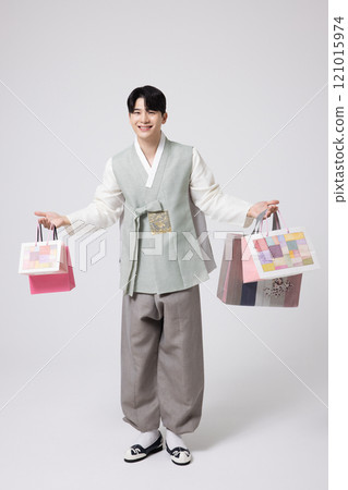 A young man wearing a hanbok and holding shopping bags in both hands 121015974