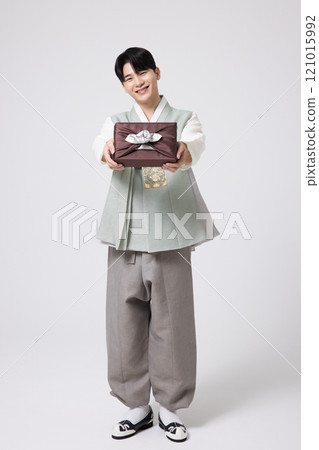 A young man wearing a hanbok and holding a carefully prepared holiday gift A young man wearing a hanbok and holding a carefully prepared holiday gift 121015992