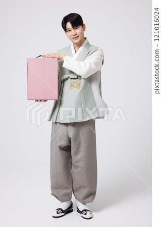 Portrait of a young man wearing hanbok and holding a holiday gift box 121016024