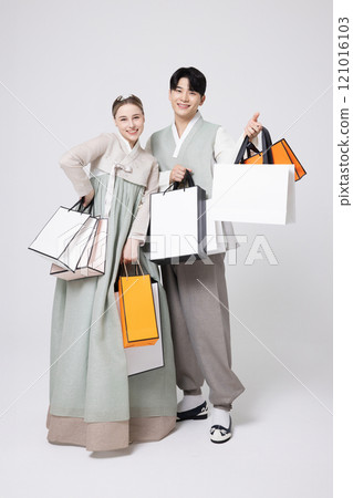 A foreign woman and a young Korean man wearing hanbok and holding shopping bags in both hands. 121016103