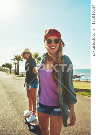 Rolling down the waterfront. Shot of two friends hanging out on the boardwalk with a skateboard. 121016184